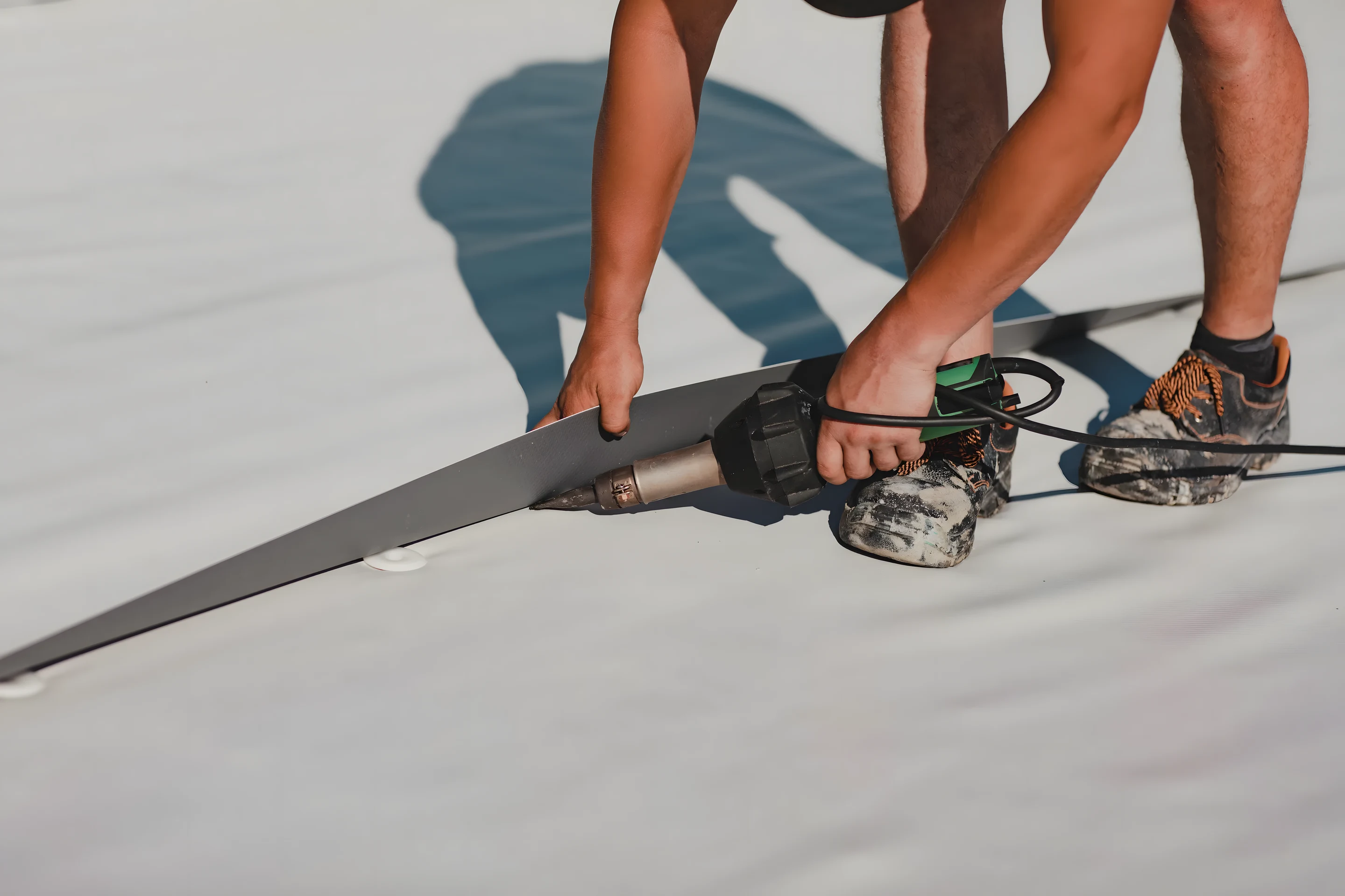 Crew hand-seaming a metal panel on a commercial standing seam roof