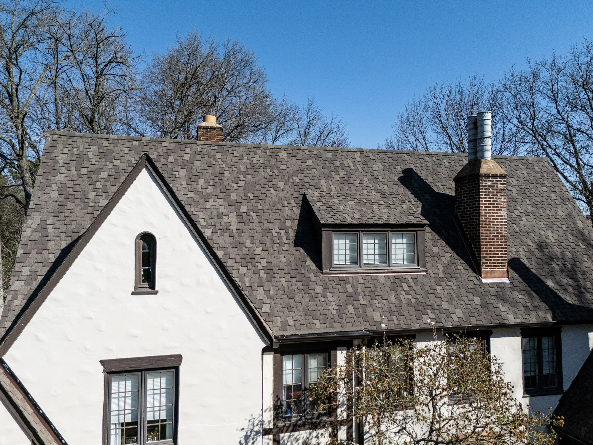 Tudor front elevation with copper awnings beneath the new designer shingle roof