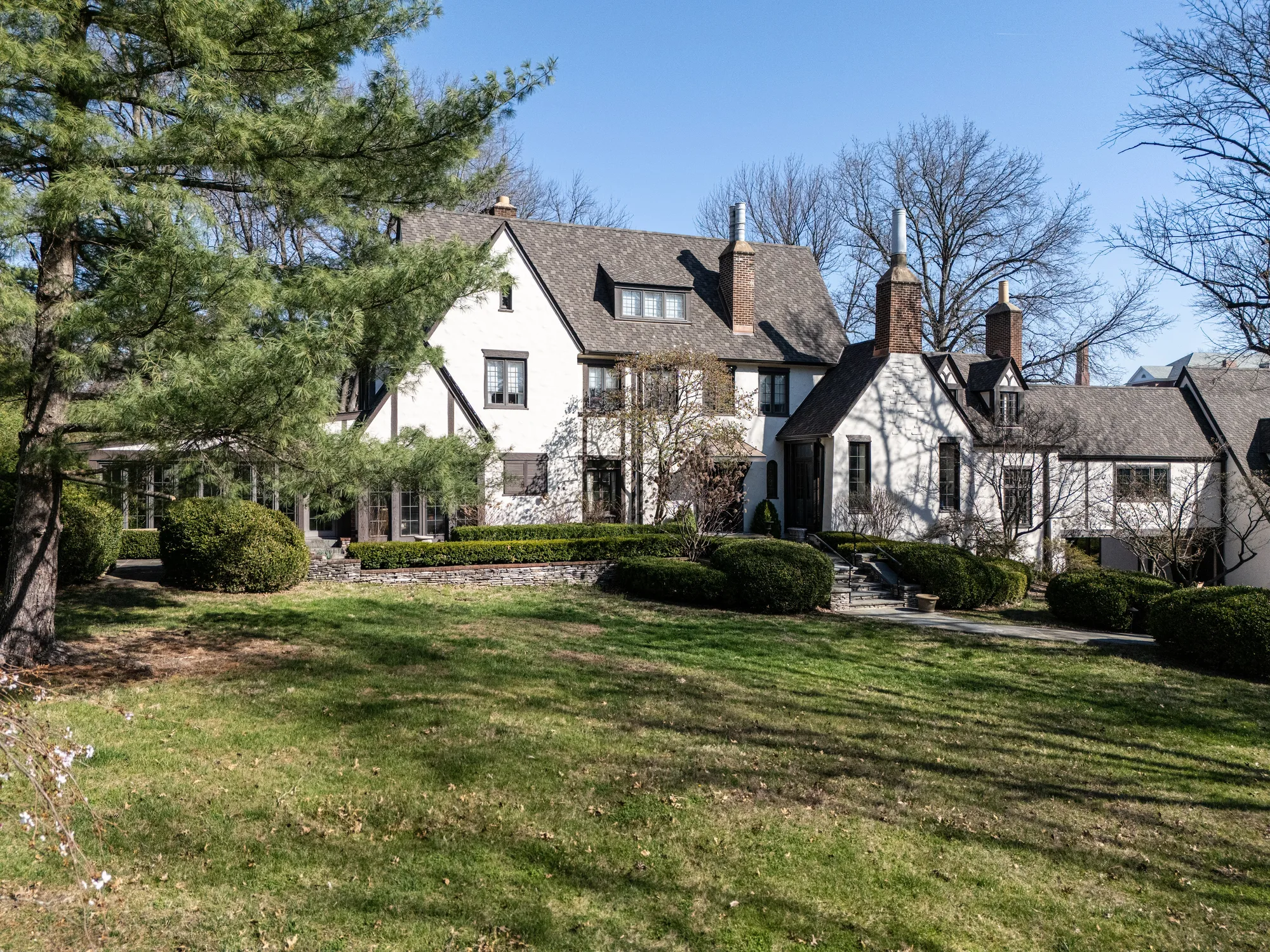 The Tudor estate across its front lawn under a finished dimensional shingle roof