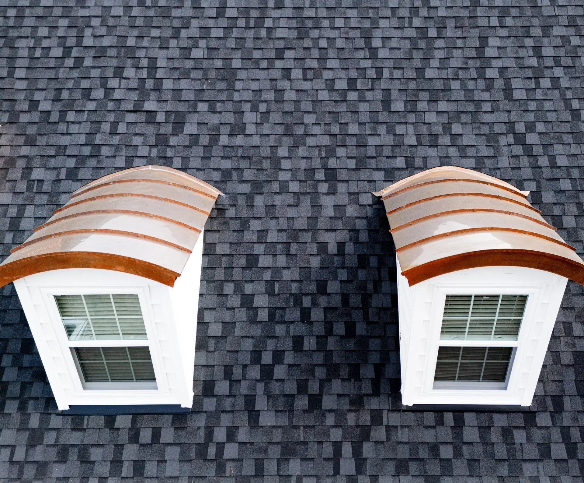 Soldered copper barrel-dormer roofs set into a slate-gray shingle field