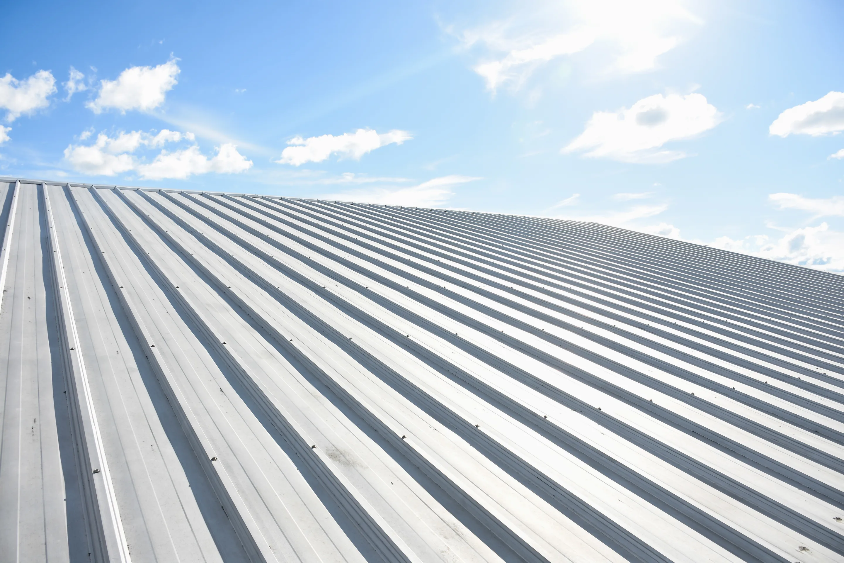 Standing seam metal roof with crisp vertical seams against a blue Midwestern sky