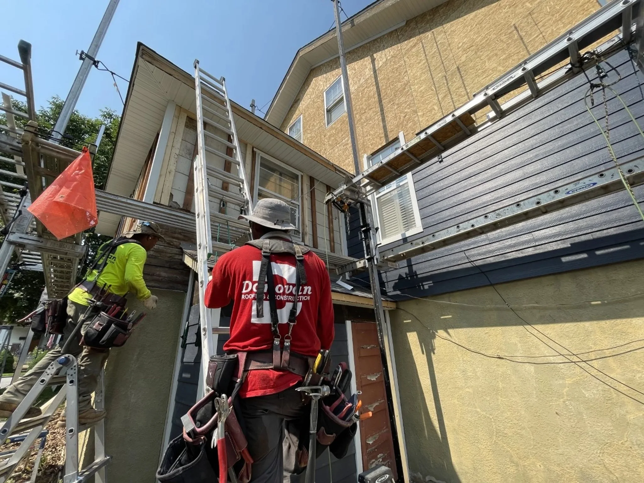 Donovan crew installing lap siding over sheathing from ladders