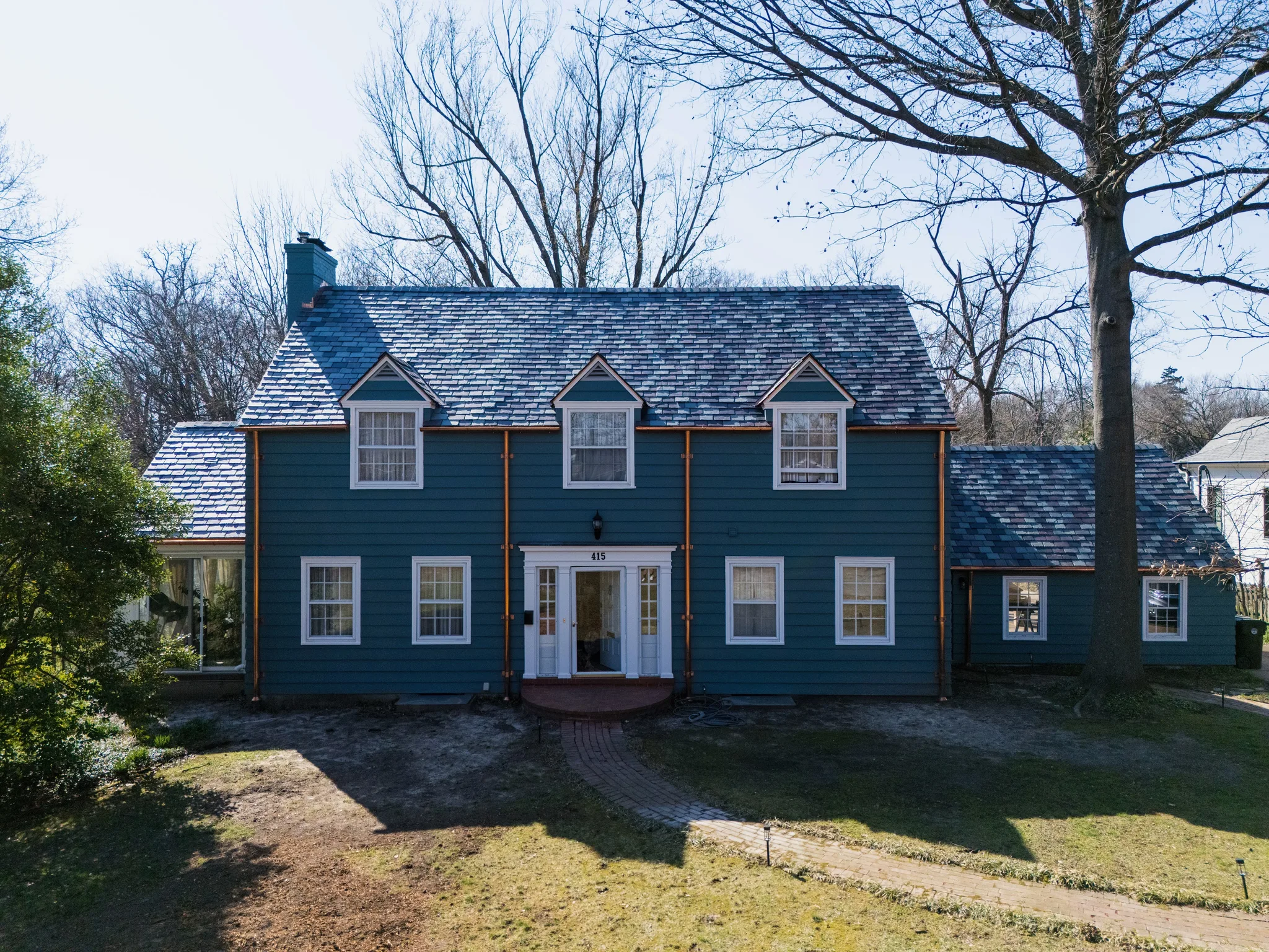 Teal fiber cement lap siding with copper downspouts on a two-story Colonial
