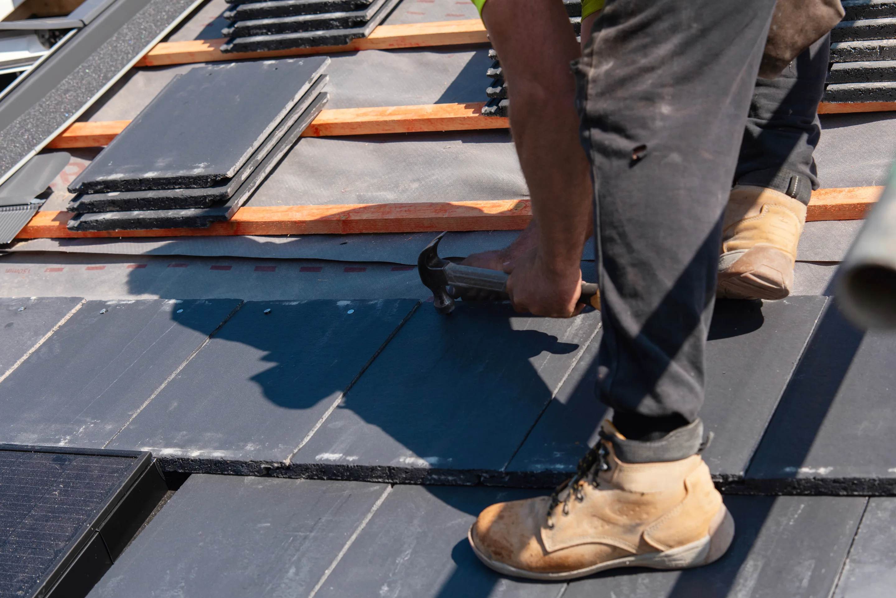 Craftsman hammering a slate course in place