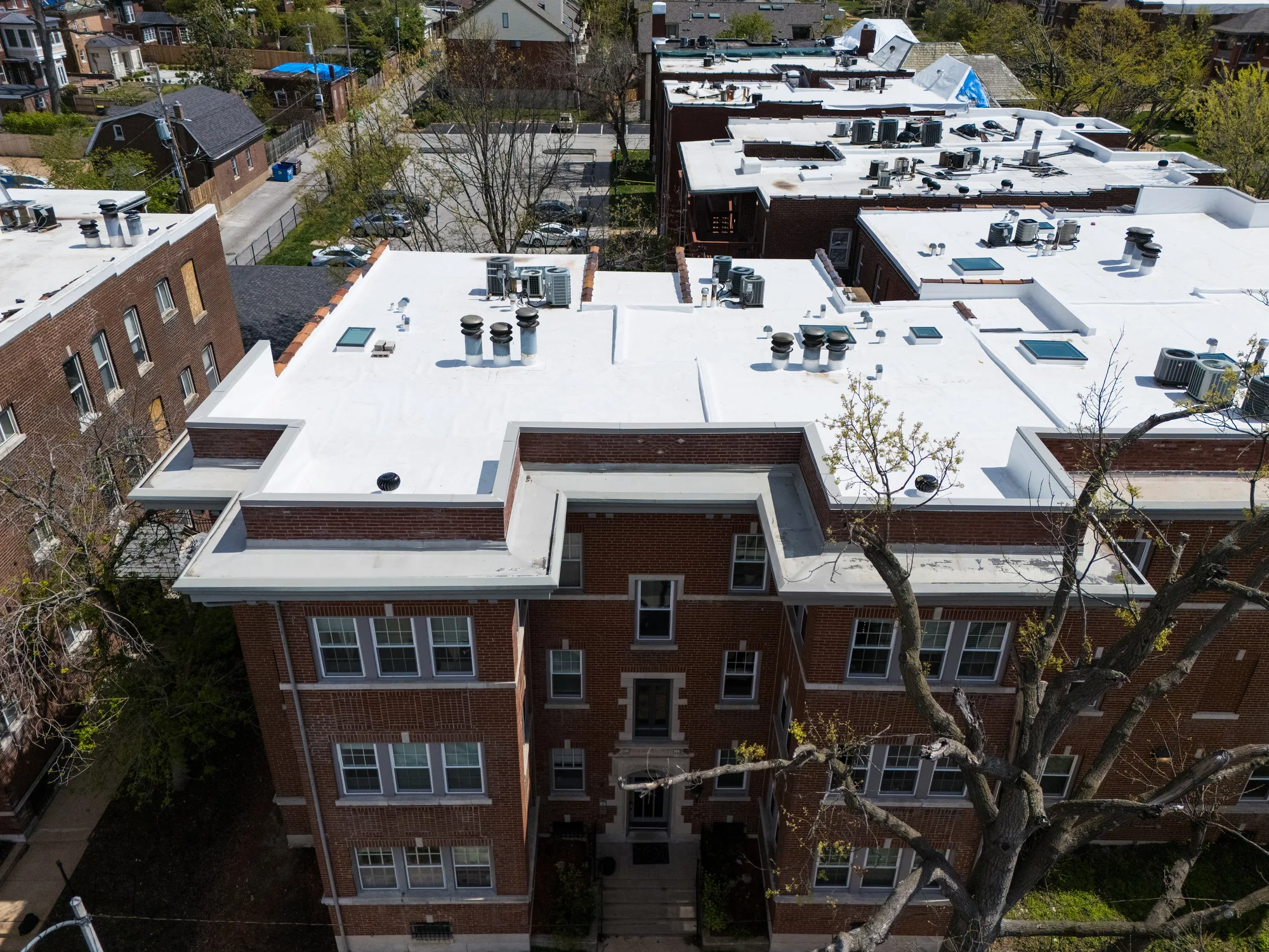 White membrane roof over the corner of a historic brick apartment building