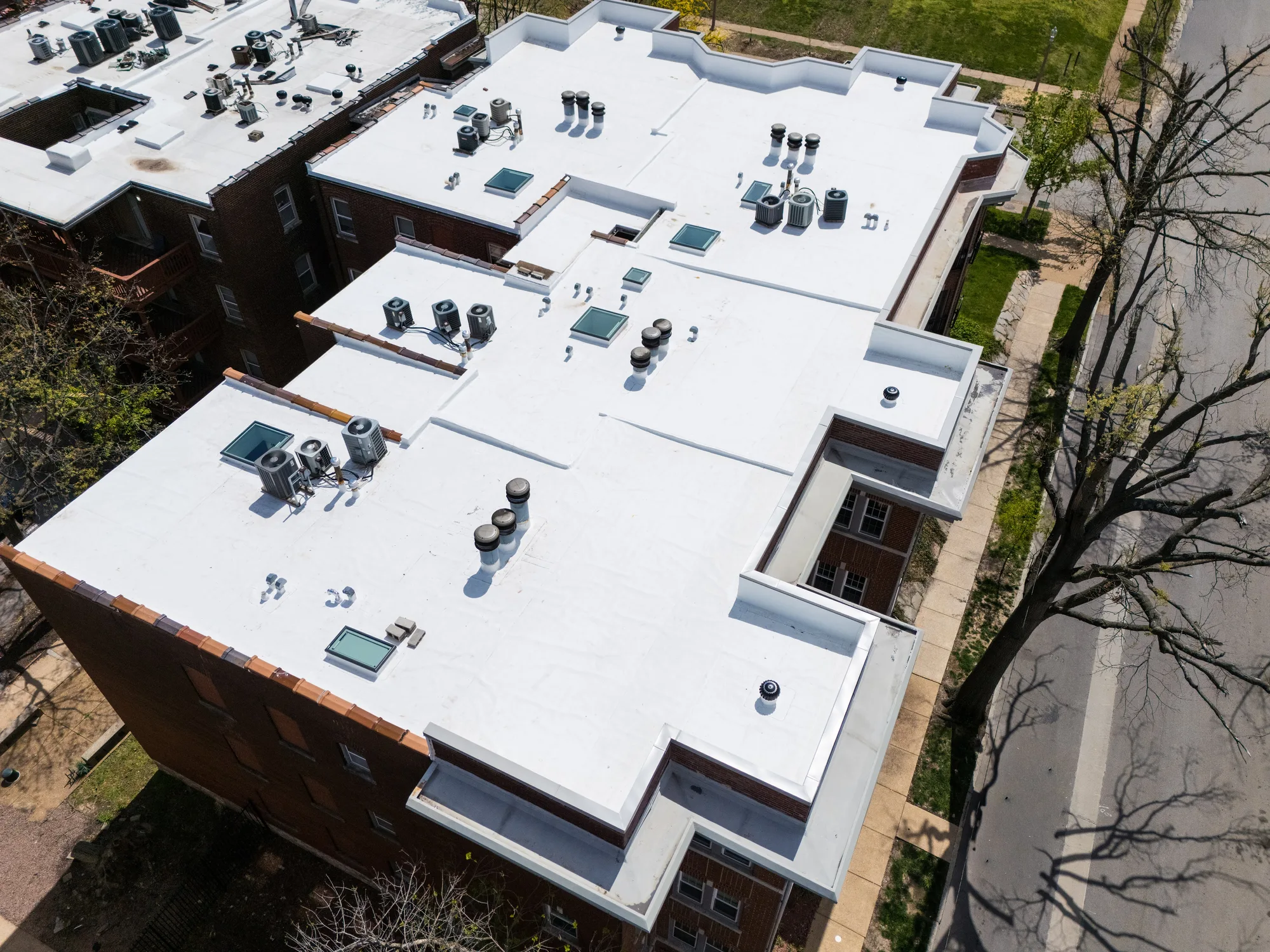 New white membrane across the wings of a historic brick apartment building