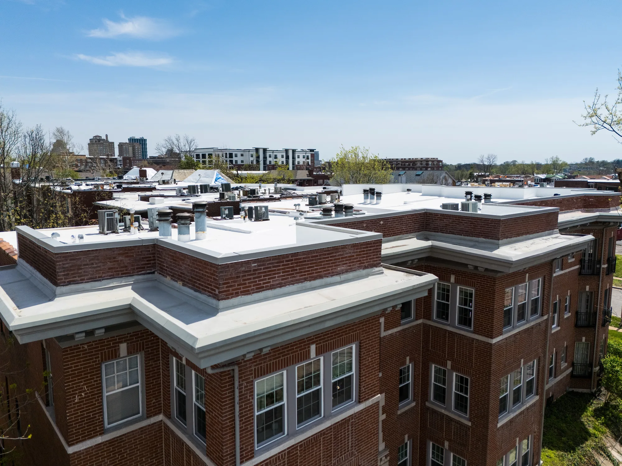 The apartment building's new membrane roof with the St. Louis skyline beyond