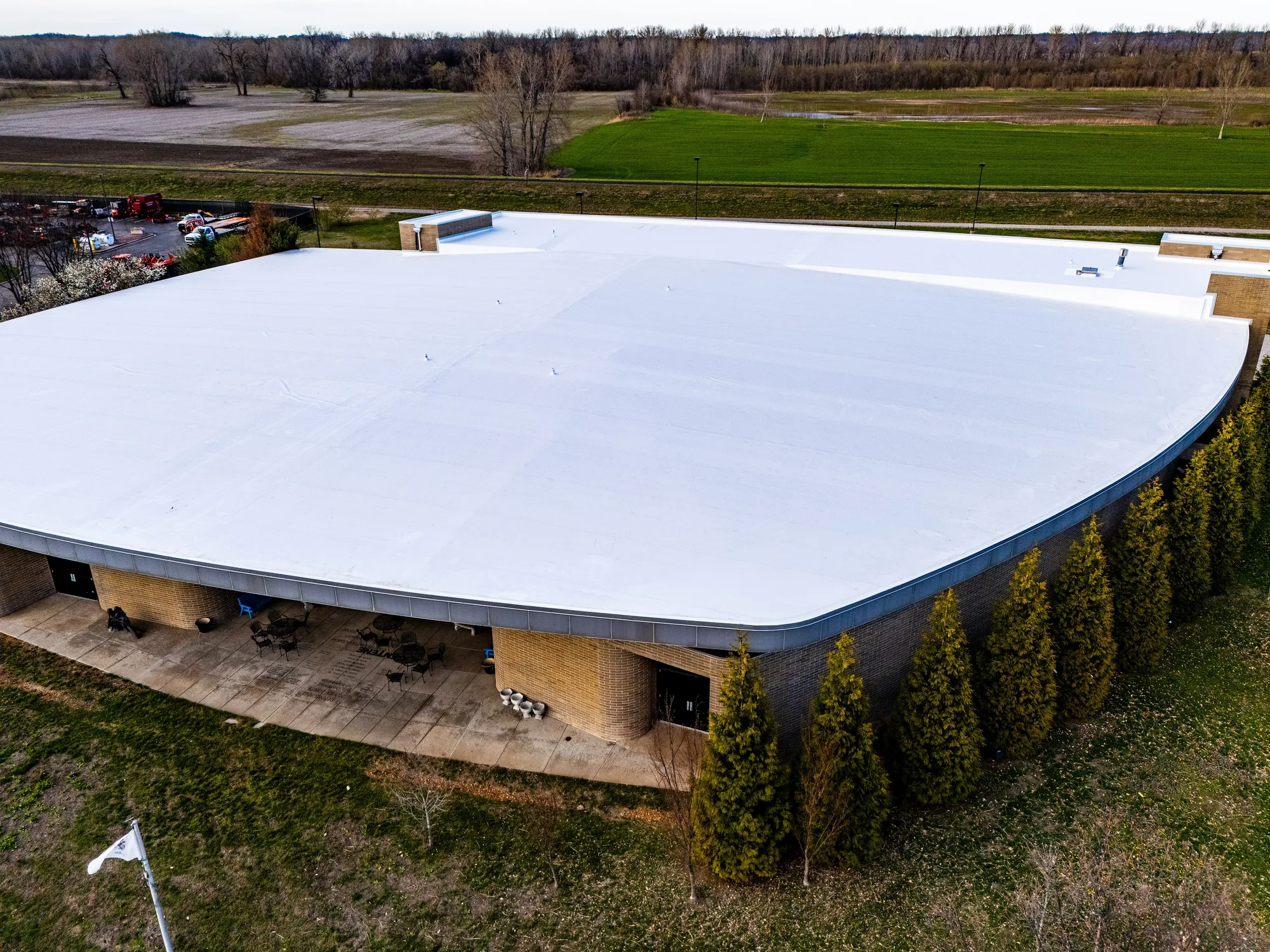 Aerial of a finished white membrane roof sweeping across a curved commercial building