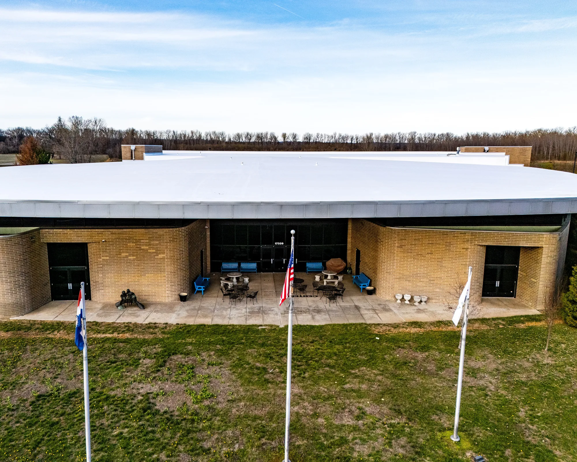 The building's entry and flagpoles beneath the finished membrane roof